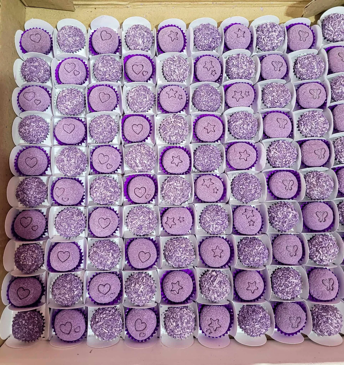 Grande encomenda de brigadeiros roxos personalizados com estrelas, corações e borboletas